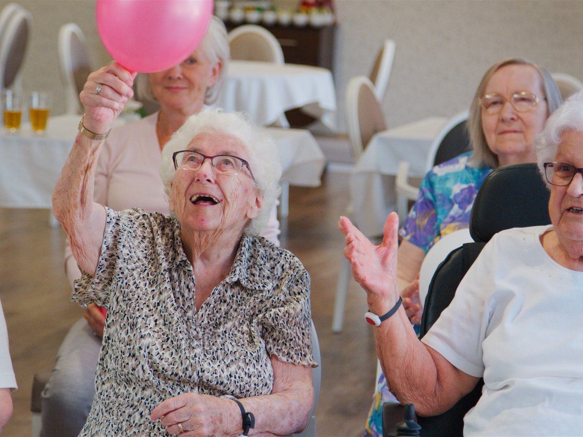 Happy seniors engaged with a balloon at an adult daycare
