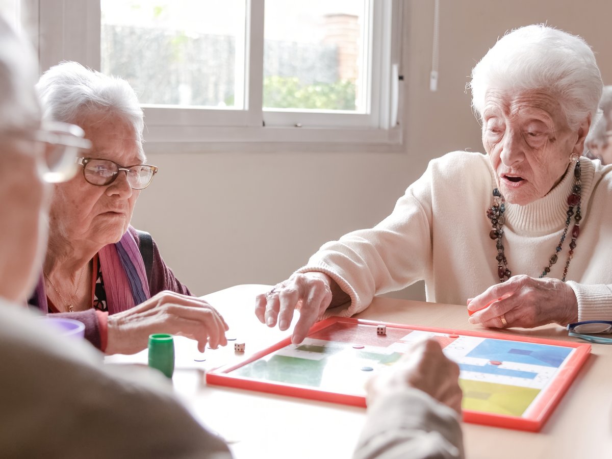 Seniors socializing while playing a board game at an adult daycare
